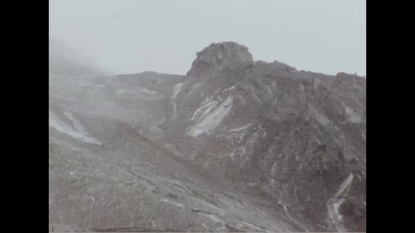 CIRCA 1980s - Aerial views of a snow Mount Saint Helens are shown. A small bird hops around in the snow. -