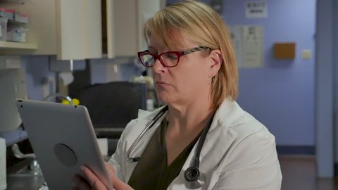 Female doctor entering medical record information on a digital tablet in a hospital or medical office in slow motion dolly shot