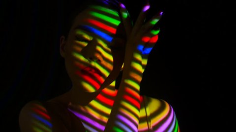 Projection of the multicolored lines on face and body of the girl. Face of girl with an abstract color pattern. Bodyart Concept. Model bodyart posing on camera.