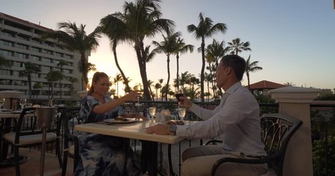 Couple Cheers Wine Glasses at Tropical Beach Restaurant, Sunset