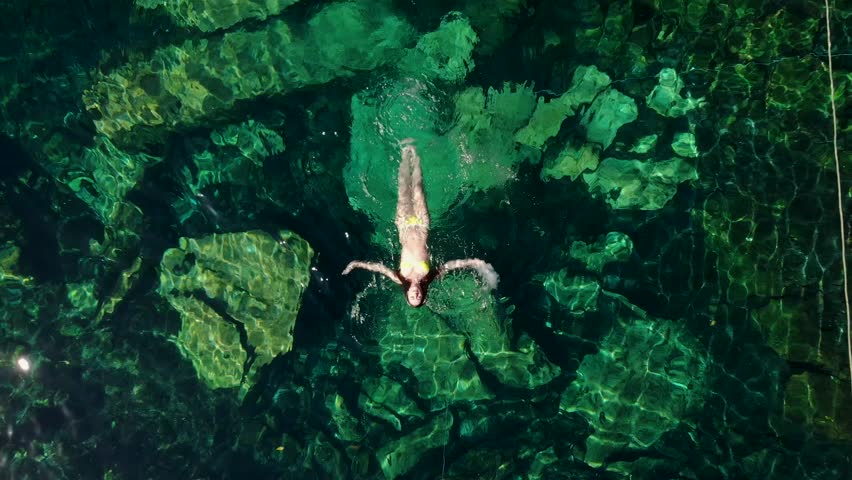 Young brunette woman floats and plays in a natural pool of a cenote in Mexico. | Shutterstock HD Video #1025299292