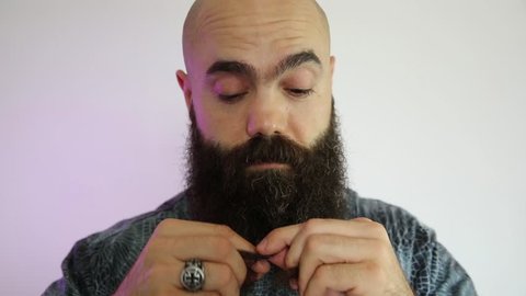Man with long beard braiding on his beard.