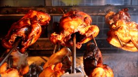 Handheld video shot of chicken and pork belly being roasted at a food store