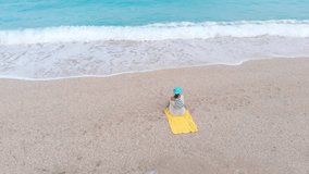 Beautiful woman on beach sitting in sand looking at ocean. Freedom and beauty. Aerial drone view