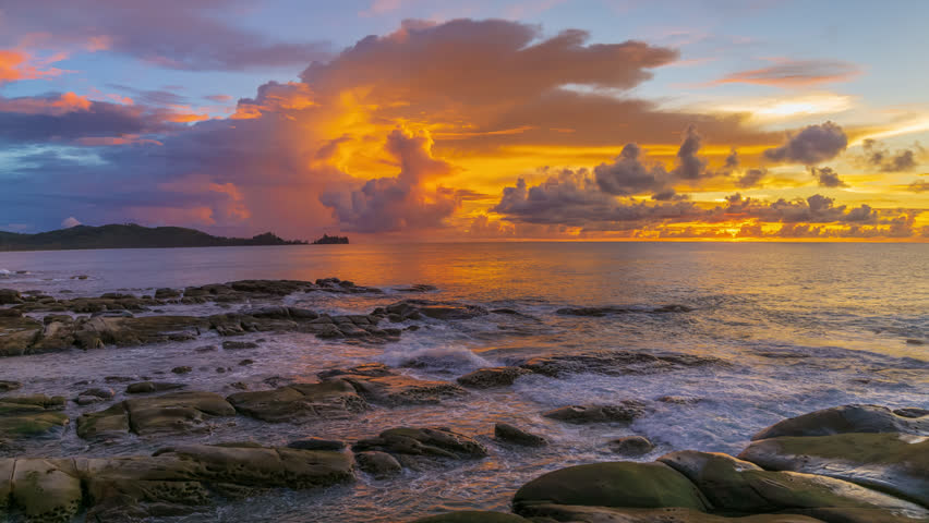 Beautiful golden sunset time lapse by a beach with big rock formation looking over the horizon in Borneo Sabah, Malaysia. Zoom in motion timelapse.
