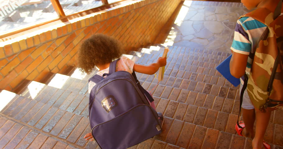 Rear view of African American school children walking down staircase of elementary school. 