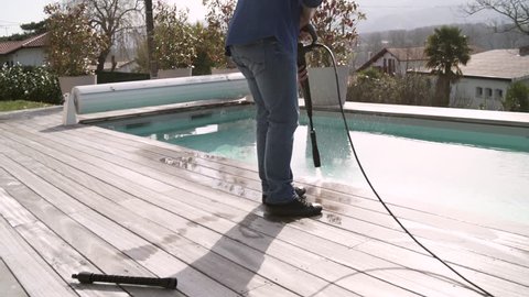 Man cleaning deck with high pressure washer