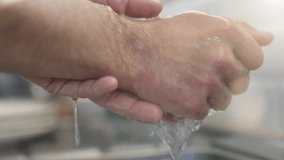 Slow motion close up of man washing his hands in kitchen