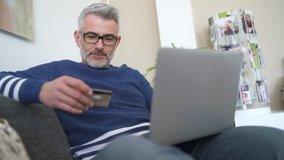 Mature man wearing glasses online shopping at home