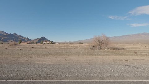 Driving West Leslie St in Pahrump Nevada with a few houses and barren desert-Drive Plate Side view-POV