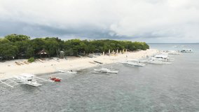 Aerial footage of Balicasag Island, Panglao, Bohol, Philippines. Tourists on the beach, stunning view on coral reef, white beach, palm trees, boats / 4K Drone Video