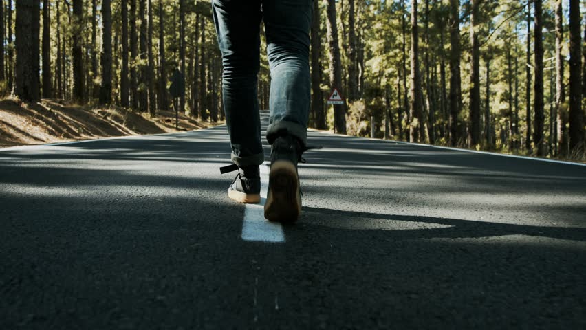 Close up follow shot of male sneackers or hiking shoes walk in middle of small mountain road in forest. Concept of walking and reaching goals. Urban nomad adventurer on hitchhiking trip | Shutterstock HD Video #1025339912