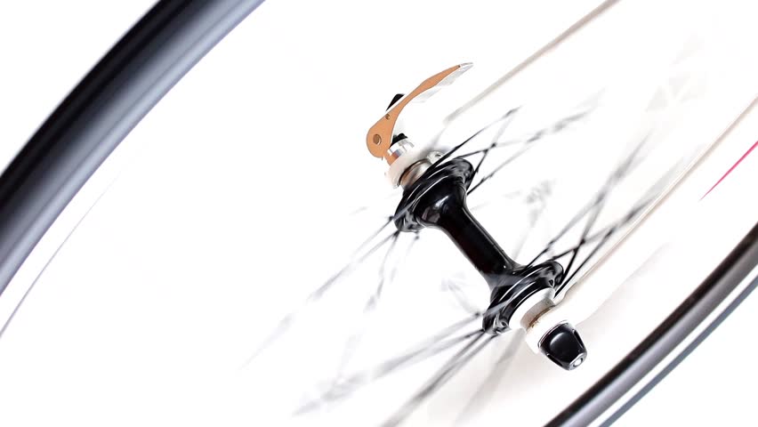 The front wheel of the bicycle rotates quickly on a white background. Detail of road bike while rotates.