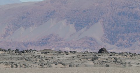 Close up of heat haze effect on black bed of lava floor. Desert color layer mountains at background. Antofagasta de la Sierra, Catamarca, Argentina