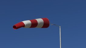 Ungraded: Windsock flutters in a strong wind showing wind direction and speed against perfect blue sky on clear summer day. Ungraded H.264 from camera without re-encoding.