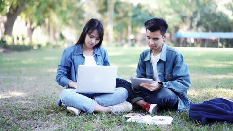 Education study abroad, group of Asian student boy with book and girl sitting at the park talking look at laptop using internet friend connection, businesswoman use computer analysis finance data
