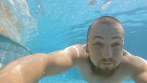 Young Man Swimming Underwater in Pool. 4K Slowmotion Gopro Selfie Travel Summer Vacation Concept. Bali, Indonesia.