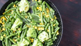 Grilling broccoli in a cast iron pan with beans and corn. slow motion