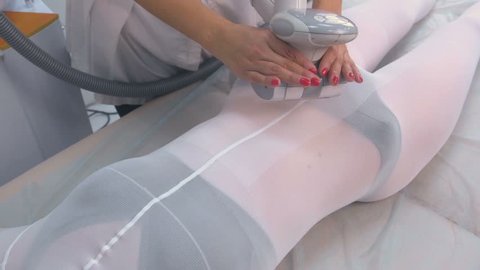 Cosmetologist makes a woman in nylon suit lpg massage on the tummy. Belly and hands close-up.