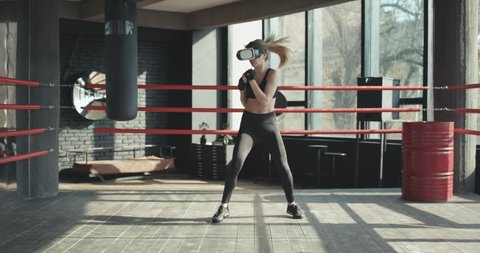 Athletic woman in vr headset boxing indoor. Young woman in sportswear using virtual reality headset. Technology concept