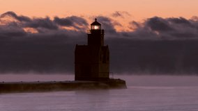 Iconic Lighthouse stands alone in frozen, steaming Lake Michigan harbor, Winter dawn time lapse.