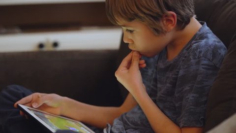 Young boy playing video game on tablet touch screen.
