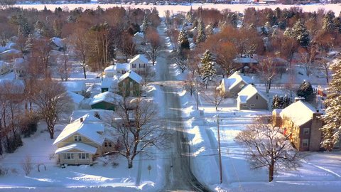 Peaceful small town under deep, fresh snow, early morning in Winter, aerial view.
