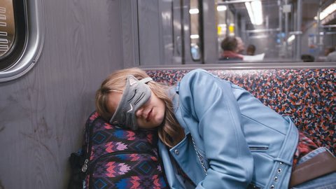 Slow Motion Young beautiful girl in the Blindfold on the eyes, fell asleep on the subway train. Head put on a backpack. The train arrives at the station. The concept of fatigue, desire to sleep.