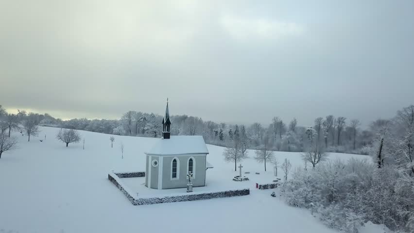 Aerial view enchanted Chapel in Winter Landscape on hill with fresh snow looking as if in a fairytale (Cinderella) in Switzerland