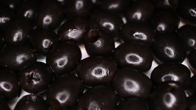 Black olives closeup texture video on rolling rotating looping plate