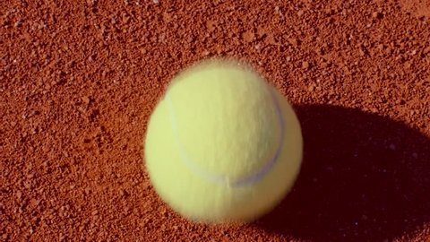Tennis player bouncing tennis ball on a red tennis court before serving. 180fps