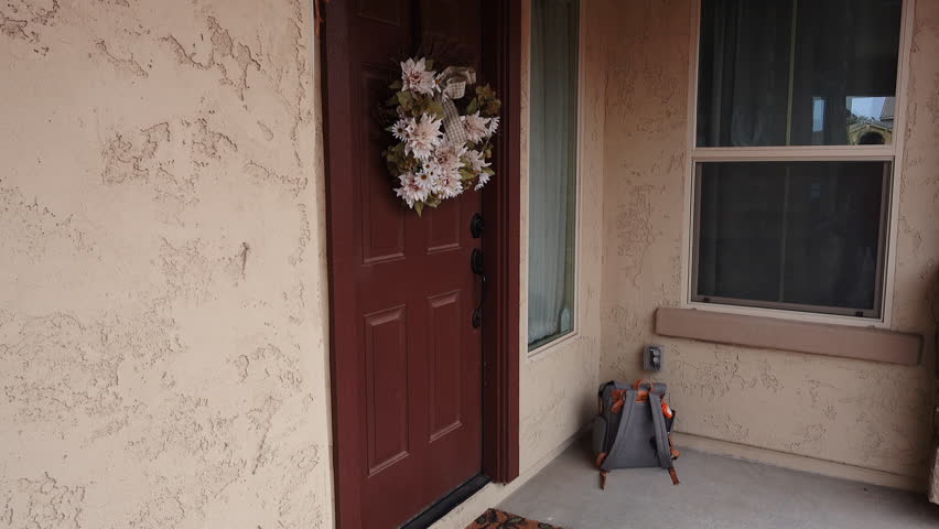 A clean video feed showing a thief stealing a backpack from the front porch of a house in broad daylight when no one is home.	 	