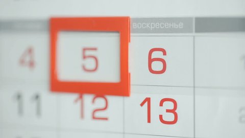 Woman's hand in office changes date at wall calendar. Changes 5 to 6