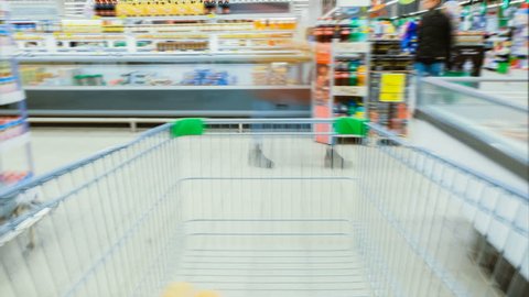 Time Lapse of the Shopping Cart Moving Between Various Aisles and Section in the Big Supermarket. Inside Trolley Various Healthy Items and Convenience Food.