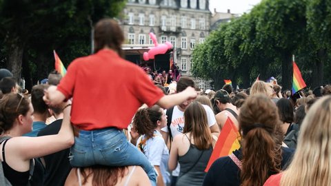 STRASBOURG, FRANCE - CIRCA 2018: Tilt-shift lens over large crowd of people waving rainbow flags at annual FestiGays pride gays and lesbians parade marching street with gay truck in front