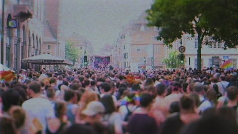 STRASBOURG, FRANCE - CIRCA 2018: VHS tape effect over large crowd of people following gay pride truck at annual FestiGays pride gays and lesbians parade marching French streets fun party atmosphere