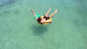 Drone point of view of young man relaxing on inflatable pineapple floating on sea. People travel beach holidays concept. Aerial view directly above of male enjoying freedom on tropical Islan vacations
