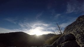 Time lapse video footage of sunset in European Alps mountains with blue sky and fast moving clouds. Airplane vapor trails, windy weather. Hiking travel and recreation concept. Action camera.