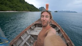 Cheerful young man takes selfie portrait on Island hopping tour in Thailand. People travel destinations vacations summer concept