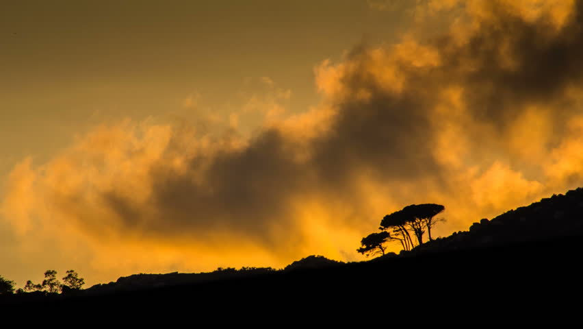 Stunning close up timelapse shot of sunset clouds behind a ridge like fire