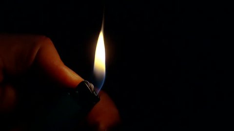 Close-up shot of a man with a lighter in dark.