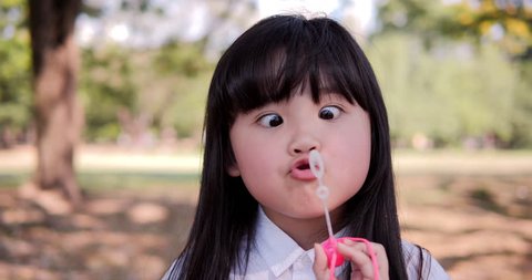 Young beautiful girl are blowing bubble with funny face at park. 4k Resolution. Slow motion shot.