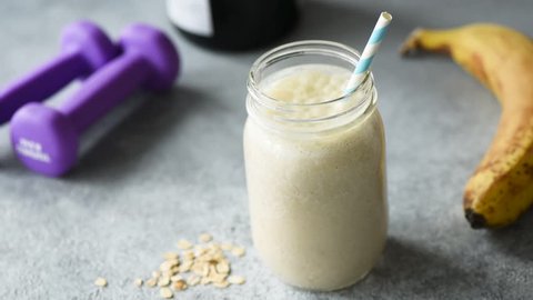 Adding protein powder into smoothie. Woman adding scoop of protein powder into breakfast smoothie. Sporty healthy lifestyle concept