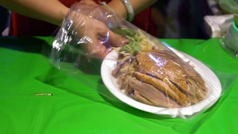 Slow Motion of asian hands of shop owner take the traditional food of chicken and ducks cut into slices for sell to people at street market in Taipei. Woman sale aliments on marketplace of Taiwan-Dan