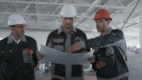 Engineer Planning Work at Machine Manufacture. Male Person in Hardhat or Protective Wear. Corporate Communication of Confident Foreman. Workman Mechanic Looking at Draft for Machinery Tool Job Indoors