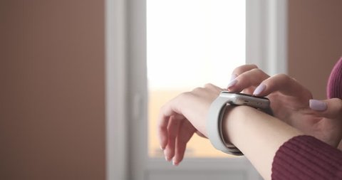 Woman using smartwatch touchscreen wearable technology device. Closeup. Smart watch on female wrist. Pretty girl making gestures on a smartwatch computer device