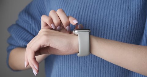 Woman using smartwatch touchscreen wearable technology device. Closeup. Smart watch on female wrist. Pretty girl making gestures on a smartwatch computer device