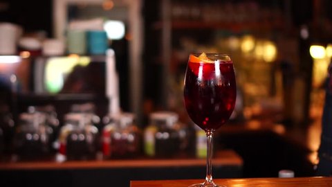 Slow motion view on classic red wine cocktail in alcohol drink glass on wooden restaurant bar counter