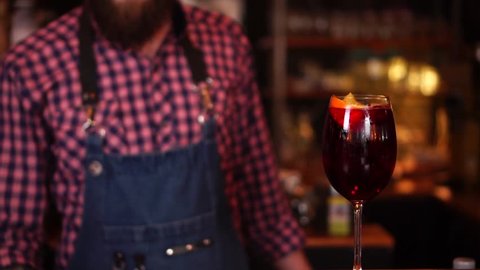Slow motion view on classic alcohol cocktail drink beverage in red wine glass on wooden bar counter
