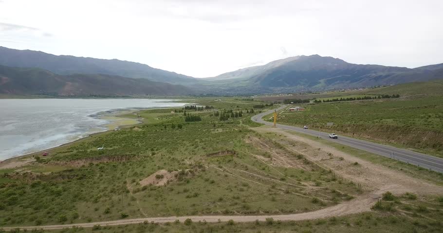 Long road adjacent to reservoir leading to vast mountain range. El Mollar.